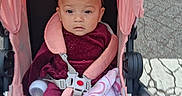 Jewlz is registered to the contest to win money with this photo: baby, child, stroller, pink, blanket, headband, sitting, portrait, face, eyes, infant, outdoor, sidewalk, pavement, harness, clothing, calm, wheel, pushchair, walk