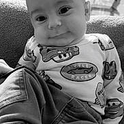 Zaylen joined the competition — help win amazing prizes! baby, child, infant, smiling, portrait, black_and_white, sitting, indoors, living_room, couch, clothing, shirt, cartoon, cars, race_cars, toy_theme, face, eyes, cozy, photography