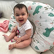 Zaya a rejoint le concours — aidez-le/la à gagner de superbes lots ! baby, child, couch, cute, face, feet, happy, head, indoor, infant, legs, onesie, pacifier, patterned_pillow, pillow, sitting, skin, smiling, toy, white_couch