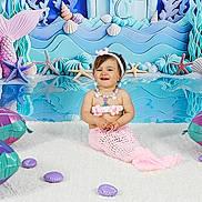 Anna a rejoint le concours — aidez-le/la à gagner de superbes lots ! toddler, child, mermaid, costume, pink, inflatable, seashell, starfish, underwater, backdrop, smiling, headband, necklace, white_rug, playful, indoor, photography, cute, happy, fantasy