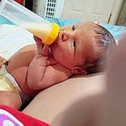 Emmanuel Malachi joined the competition — help win amazing prizes! baby, infant, bottle, milk, feeding, diaper, bed, hand, face, skin, newborn, lying_down, indoors, cute, human, child, sleepwear, relaxing, small, peaceful