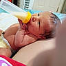 baby, infant, bottle, milk, feeding, diaper, bed, hand, face, skin, newborn, lying_down, indoors, cute, human, child, sleepwear, relaxing, small, peaceful