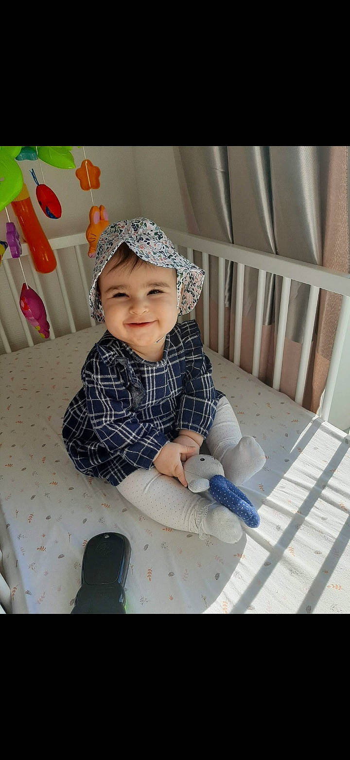 Emilie a rejoint le concours — aidez-le/la à gagner de superbes lots ! baby, baby_products, baby_toddler_clothing, beanie, cap, child, comfort, fashion_accessory, flooring, fun, happy, headwear, joy, laugh, pattern, person, portrait_photography, sitting, sleeve, smile