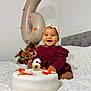 baby, smiling, birthday, cake, balloon, number_6, flower_arrangement, headband, dress, bed, white_bedspread, celebration, indoor, happy, child, portrait, sitting, decorations, orange_bows, photography
