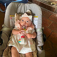 Anaïa participe au concours pour gagner de l'argent avec cette photo : baby, infant, child, baby_carrier, toy, rattle, dress, headband, pink, white, clothing, floor, brick, indoor, person, cute, sitting, wide_eyes, hand, carrying
