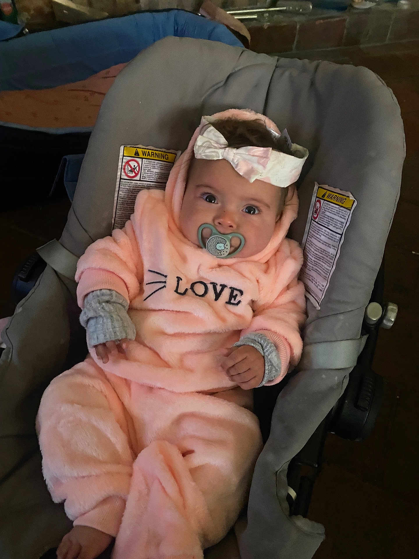 Anaïa a rejoint le concours — aidez-le/la à gagner de superbes lots ! baby, infant, pacifier, headband, car_seat, pink_clothing, cozy, cute, child, indoor, warm_clothing, portrait, sitting, face, hands, footwear, warning_label, fabric, soft_texture, love