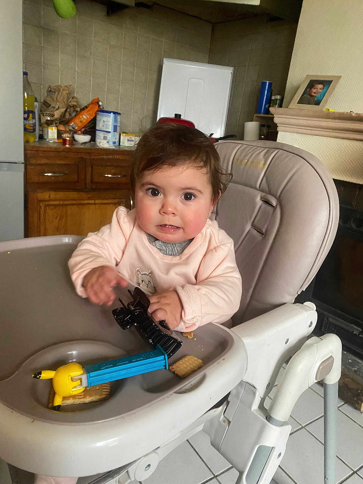 Anaïa a rejoint le concours — aidez-le/la à gagner de superbes lots ! child, baby, toddler, highchair, toy, cracker, snack, crumbs, hair_clip, kitchen, cabinet, framed_photo, portrait, tray, clothing, face, expression, indoor, plastic_toy, brown_hair