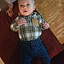 Charles joined the competition — help win amazing prizes! baby, child, plaid_shirt, blue_pants, lying_down, wooden_board, hand, indoor, curious_expression, footwear, fabric, person, skin, face, young_child, casual_clothing, home, floor, red_fabric, light