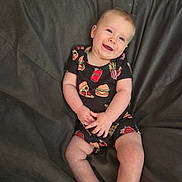 Charles joined the competition — help win amazing prizes! baby, child, smiling, infant, clothing, black_onesie, fast_food_pattern, pizza, burger, fries, soda_can, couch, fabric, comfortable, happy, portrait, sitting, cute, skin, hands