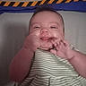 Sofia is registered to the contest to win money with this photo: baby, blanket, cheeks, child, cute, expression, face, hand, happy, indoor, infant, lying_down, person, playful, skin, smiling, soft_surface, striped_clothing, toddler, young