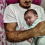 Kennedy is registered to the contest to win money with this photo: baby, bed, bedding, cuddling, embracing, family, father, floral, indoors, infant, newborn, onesie, parent, peaceful, pillow, portrait, sleeping, striped_clothing, tattoo, white_shirt