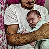 baby, bed, bedding, cuddling, embracing, family, father, floral, indoors, infant, newborn, onesie, parent, peaceful, pillow, portrait, sleeping, striped_clothing, tattoo, white_shirt