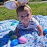 Ashton is registered to the contest to win money with this photo: baby, bunny_ears, easter_eggs, blanket, outdoor, grass, sunlight, child, cute, infant, blue, pink, green, white_clothing, pattern, nature, toy, holiday, spring, portrait
