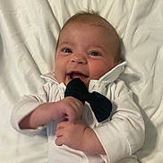 Ashton joined the competition — help win amazing prizes! baby, infant, smile, white_clothing, bow_tie, lying_down, blanket, happy, cute, child, face, hands, indoors, portrait, newborn, soft, young, person, closeup, skin