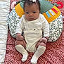 baby, infant, bow, socks, blanket, pillow, patterned, polka_dot, white_clothing, cute, indoors, child, face, sitting, toy, colorful, soft, young, portrait, looking