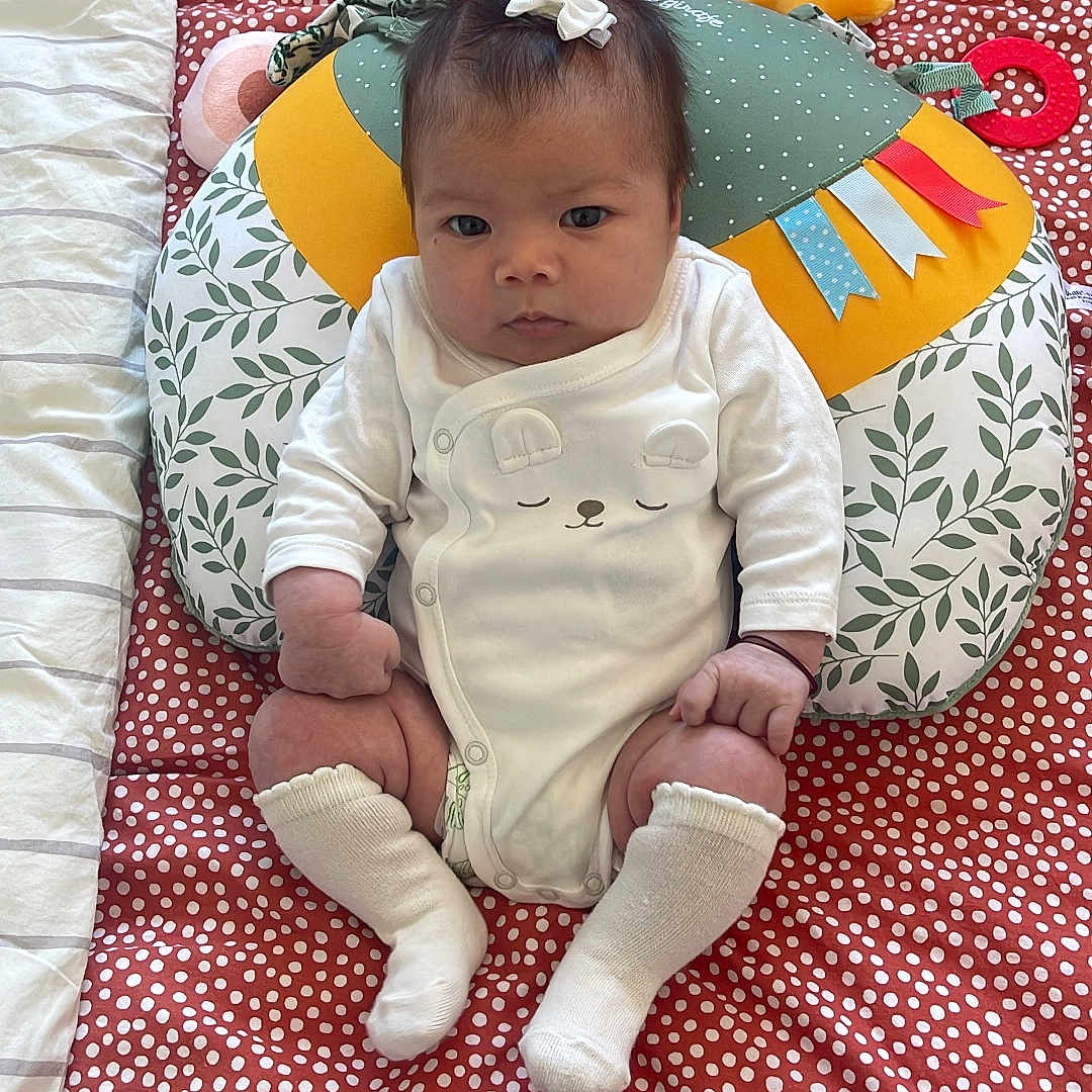 Xuân Lan a rejoint le concours — aidez-le/la à gagner de superbes lots ! baby, blanket, bow, child, colorful, cute, face, indoors, infant, looking, patterned, pillow, polka_dot, portrait, sitting, socks, soft, toy, white_clothing, young