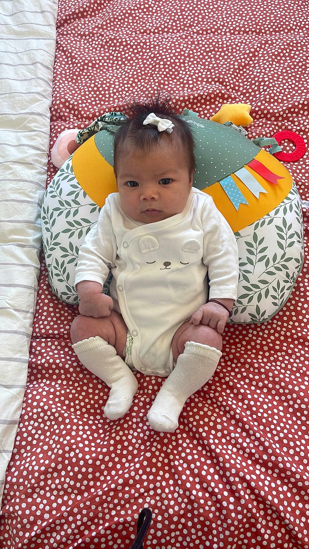 Xuân Lan a rejoint le concours — aidez-le/la à gagner de superbes lots ! baby, infant, bow, socks, blanket, pillow, patterned, polka_dot, white_clothing, cute, indoors, child, face, sitting, toy, colorful, soft, young, portrait, looking