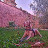 dog, brown_dog, pet, animal, outdoor, garden, grass, greenery, stone_wall, brick_wall, nature, backyard, lying_down, harness, collar, portrait, animal_face, floppy_ears, autumn, plants