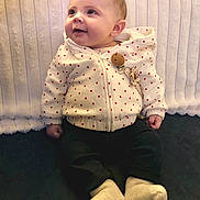 Romy a rejoint le concours — aidez-le/la à gagner de superbes lots ! baby, child, hoodie, white_clothing, red_hearts, sitting, smiling, happy, face, infant, cute, cozy, warm_clothing, socks, indoor, portrait, young_child, looking_up, soft_background, casual