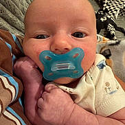 River is registered to the contest to win money with this photo: baby, infant, pacifier, close_up, face, hand, blanket, clothing, striped, comfort, cute, newborn, skin, expression, young_child, portrait, indoors, soft_texture, resting, peaceful