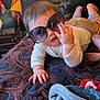 baby, sunglasses, blanket, indoor, child, hand, face, furniture, chair, pattern, clothing, person, cute, portrait, toddler, soft, cozy, relaxed, infant, home
