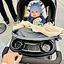 Abraham is registered to the contest to win money with this photo: baby, stroller, child, blue_hat, blanket, hand, person, floor, clothing, seat, indoor, toy_bracelet, footwear, black_pants, plastic, fabric, person_walking, grip, curious, wide_eyes