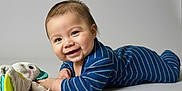 Abraham is registered to the contest to win money with this photo: baby, smile, onesie, striped_clothing, toy, plush_toy, tummy_time, infant, cute, happy, child, face, skin, head, hand, floor, indoor, portrait, young_child, playtime