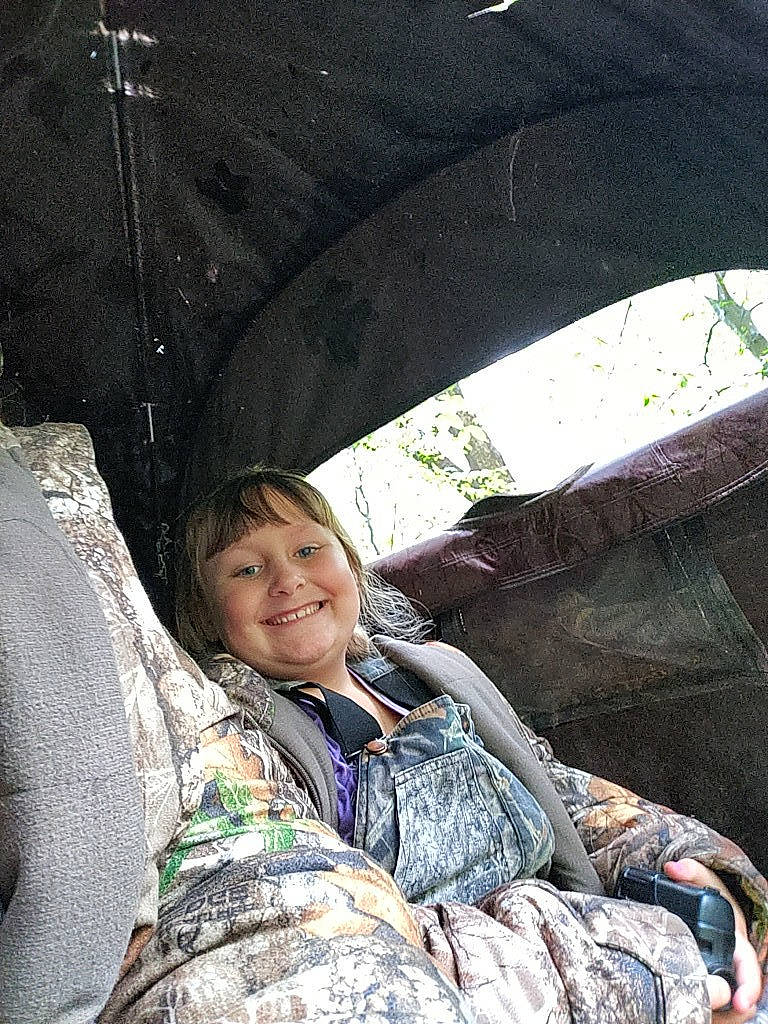 Bethany is registered to the contest to win money with this photo: auto_part, automotive_exterior, automotive_tire, automotive_wheel_system, child, eye, fun, grass, joy, leisure, military_camouflage, motor_vehicle, person, plant, rock, sitting, smile, tints_and_shades, travel, tree