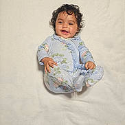 Izabella joined the competition — help win amazing prizes! baby, infant, smiling, onesie, blanket, carpet, curly_hair, happy, child, lying_down, indoors, person, footwear, patterned_clothing, cute, portrait, soft_texture, relaxed, young_child, playful