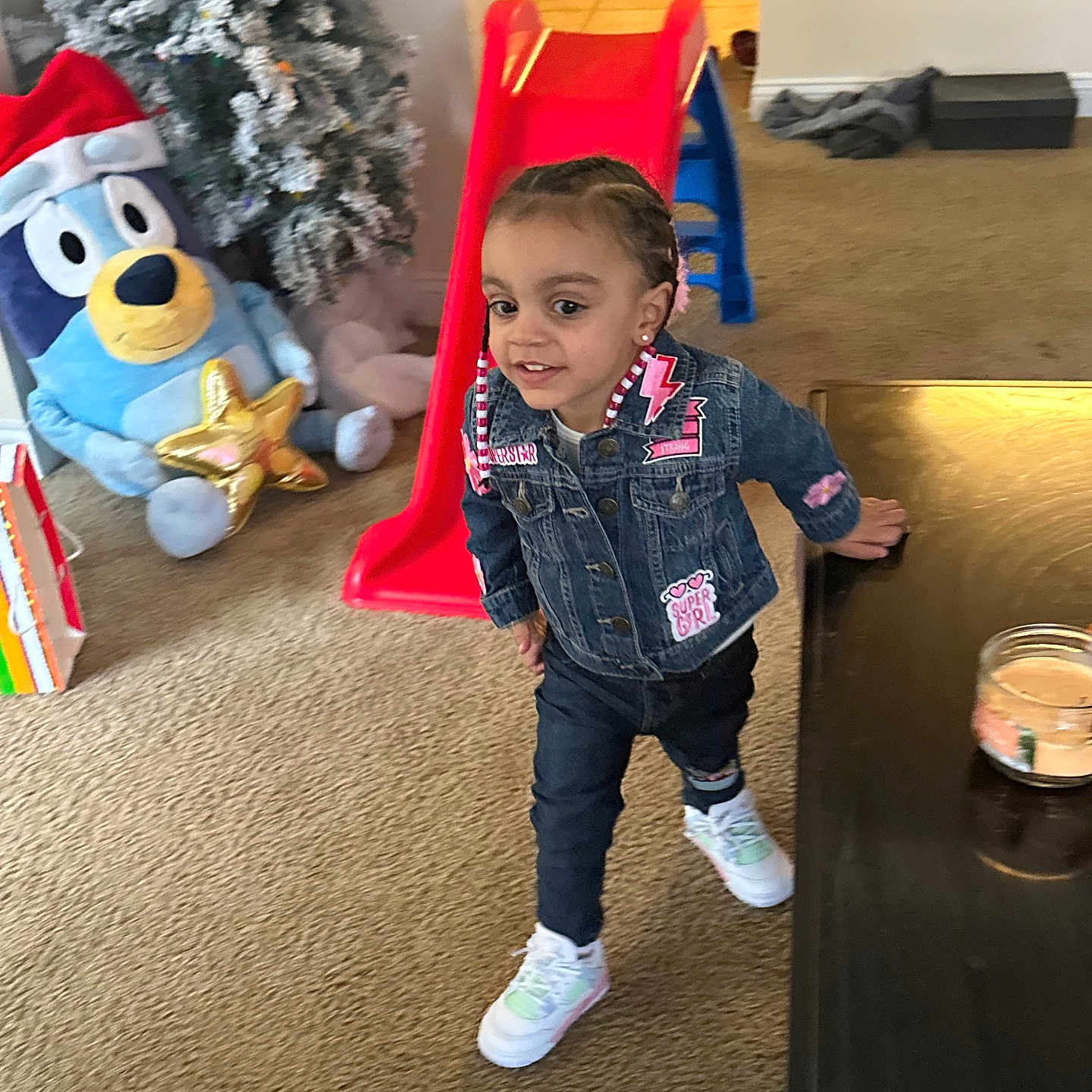 Ari Isiabell is registered to the contest to win money with this photo: candle, carpet, child, denim_jacket, earrings, hair_braids, holiday, home, indoor, jeans, person, play, plush_toy, red_slide, santa_hat, smiling, table, toddler, toy, white_sneakers