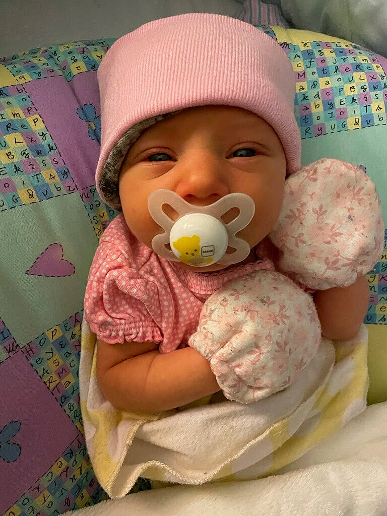 Juniper is registered to the contest to win money with this photo: baby, baby_products, baby_sleeping, baby_toddler_clothing, cap, cheek, child, comfort, drinkware, face, facial_expression, finger, happy, headgear, headwear, linens, nose, person, pink, skin