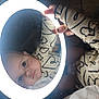 baby, child, face, reflection, mirror, circular_light, hand, sweater, heart_pattern, wide_eyes, portrait, indoor, cute, expression, skin, nail, ring, cozy, soft_light, curious