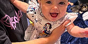 Layla joined the competition — help win amazing prizes! baby, child, smiling, headband, dress, person, adult, hand, bed, blanket, dog, hair, footwear, indoor, toy, furniture, window, curtain, happy, skin