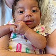 Alani is registered to the contest to win money with this photo: baby, infant, child, person, holding, arms, close_up, cute, smiling, onesie, colorful_clothing, popsicle_pattern, skin, face, eyes, hands, adult, love, comfort, family