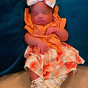 Adaeze is registered to the contest to win money with this photo: baby, infant, sleeping, headband, bow, dress, floral_pattern, socks, shoes, couch, cushion, indoor, person, child, cute, resting, hands, face, footwear, relaxation
