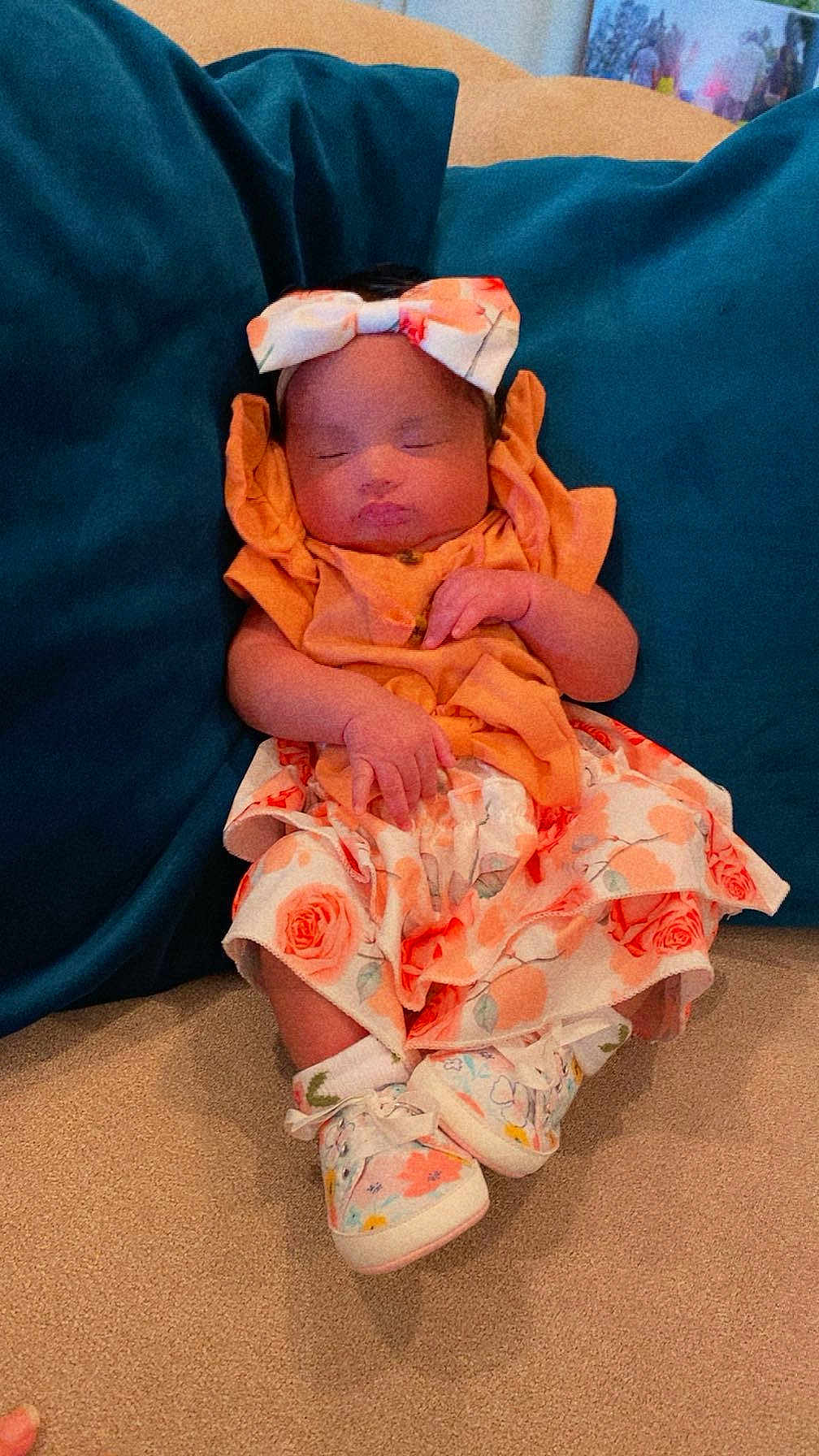 Adaeze is registered to the contest to win money with this photo: baby, infant, sleeping, headband, bow, dress, floral_pattern, socks, shoes, couch, cushion, indoor, person, child, cute, resting, hands, face, footwear, relaxation