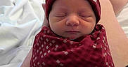 River joined the competition — help win amazing prizes! newborn, baby, sleeping, swaddle, beanie, red_clothing, tattoo, arm, lap, blanket, bed, indoor, portrait, person, infant, resting, peaceful, cute, closeup, human