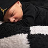 River is registered to the contest to win money with this photo: baby, newborn, sleeping, black_clothing, hat, blanket, texture, closeup, face, peaceful, infant, resting, soft, cozy, portrait, child, cute, indoors, headwear, black_and_white
