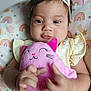 baby, child, plush_toy, pink, bow, headband, cushion, rainbow, stars, yellow_dress, indoor, closeup, smiling, cute, infant, soft_toy, hands, face, happy, portrait