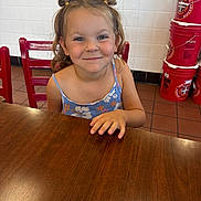 Mila joined the competition — help win amazing prizes! child, girl, smiling, portrait, indoors, restaurant, table, chair, red_buckets, tiled_wall, floral_dress, pigtails, brown_hair, blue_eyes, sitting, hand, wooden_table, happy, food_service, photography