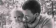Khaleesi is registered to the contest to win money with this photo: affection, baby, black_and_white, child, clothing, cute, face, family, forest, hair, holding, man, nature, outdoor, parent, person, portrait, smile, tender_moment, young_child