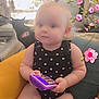 armchair, baby, black_clothing, cat, chair, child, curly_hair, cute, flower_stickers, furniture, indoors, living_room, person, pet, playful, plush, polka_dot, seated, toddler, toy_phone