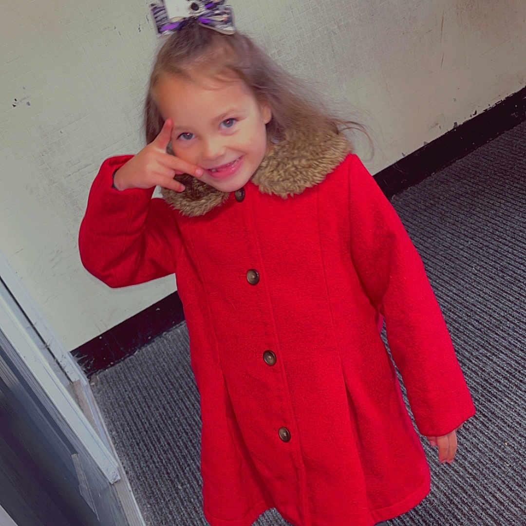 Aurora-May is registered to the contest to win money with this photo: bow, buttoned_coat, carpet, casual, child, cute, fashion, footwear, girl, hair_accessory, happy, indoor, pants, person, playful, posing, red_coat, smiling, wall, young