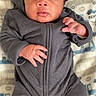 baby, infant, onesie, gray_clothing, blanket, patterned_blanket, blue, orange, white, vehicle_print, hands, face, curious, lying_down, portrait, cute, newborn, soft_lighting, indoors, child