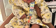 Syncerely joined the competition — help win amazing prizes! baby, infant, hooded_robe, pacifier, colorful_clip, bare_feet, hands, adult, indoor, living_room, television, furniture, person, cute, soft_texture, warm_clothing, close_up, portrait, expression, holding