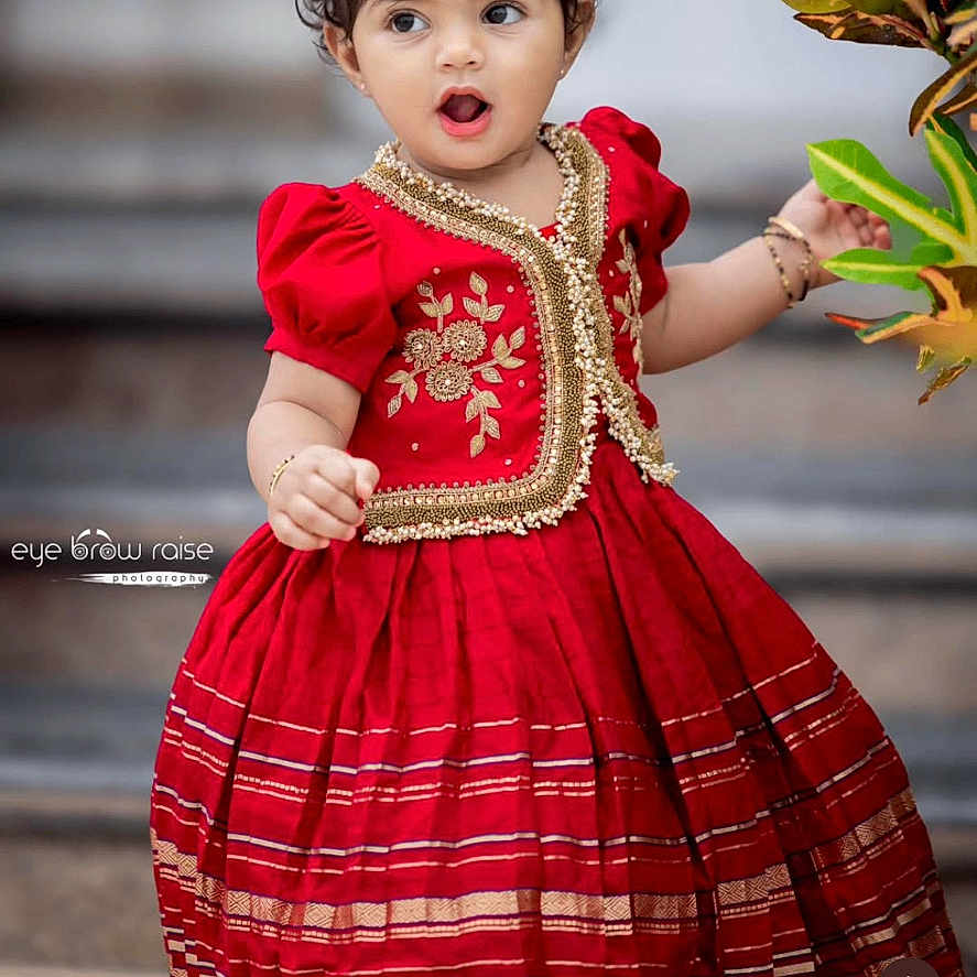 Janhvi joined the competition — help win amazing prizes! toddler, child, red_dress, traditional_clothing, curly_hair, outdoor, plant, foliage, steps, portrait, cute, fashion, young_child, expression, bracelet, hair_accessory, social_media_post, text_overlay, people, photography