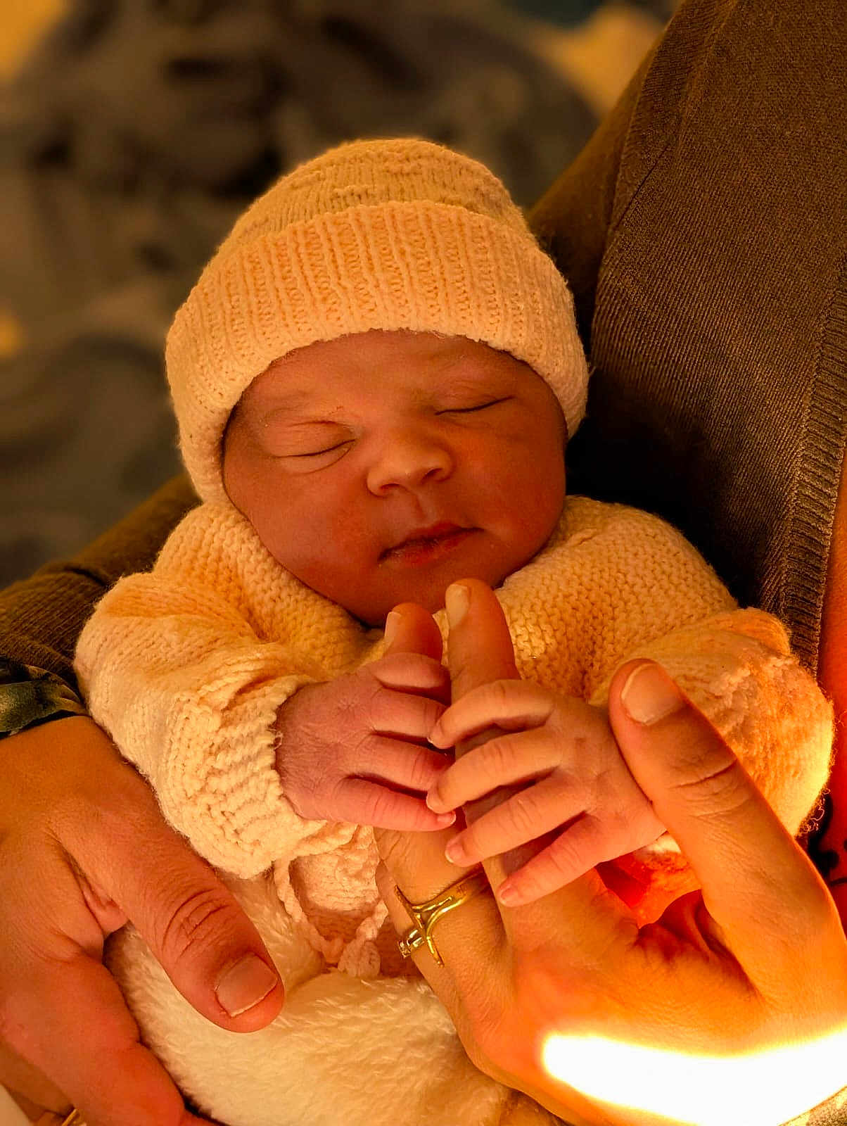 Akasya participe au concours pour gagner de l'argent avec cette photo : baby, newborn, infant, hands, knitted_hat, knitted_sweater, sleeping, closeup, warm_lighting, human, person, skin, cute, tender, love, family, newborn_clothing, soft_texture, holding, peaceful