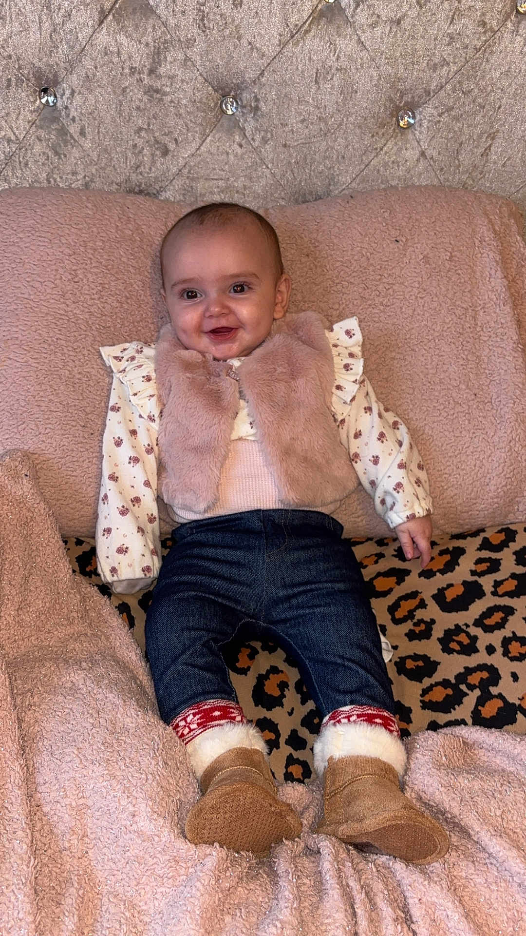 Elsie joined the competition — help win amazing prizes! baby, child, smiling, indoor, blanket, fur_vest, boots, jeans, patterned_shirt, leopard_print, cushion, cozy, soft_texture, happy, portrait, clothing, person, infant, cute, warm