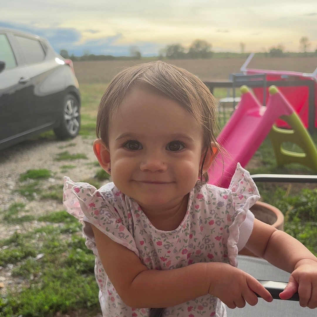 Lyse a rejoint le concours — aidez-le/la à gagner de superbes lots ! car, chair, child, cloudy, concrete, daylight, flower_pattern, grass, happy, jeans, nature, outdoor, person, playground, short_sleeves, sky, slide, smiling, toddler, young_child