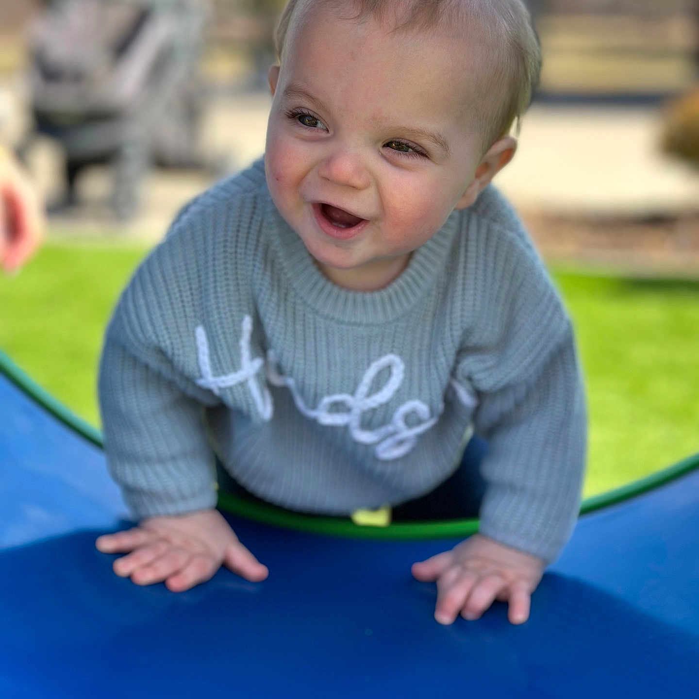 Hudson is registered to the contest to win money with this photo: baby, bodypart, clothing, crawling, face, finger, grass, happy, head, knitwear, outdoorplayarea, outdoors, person, photography, plant, playarea, portrait, slide, sweater, toy